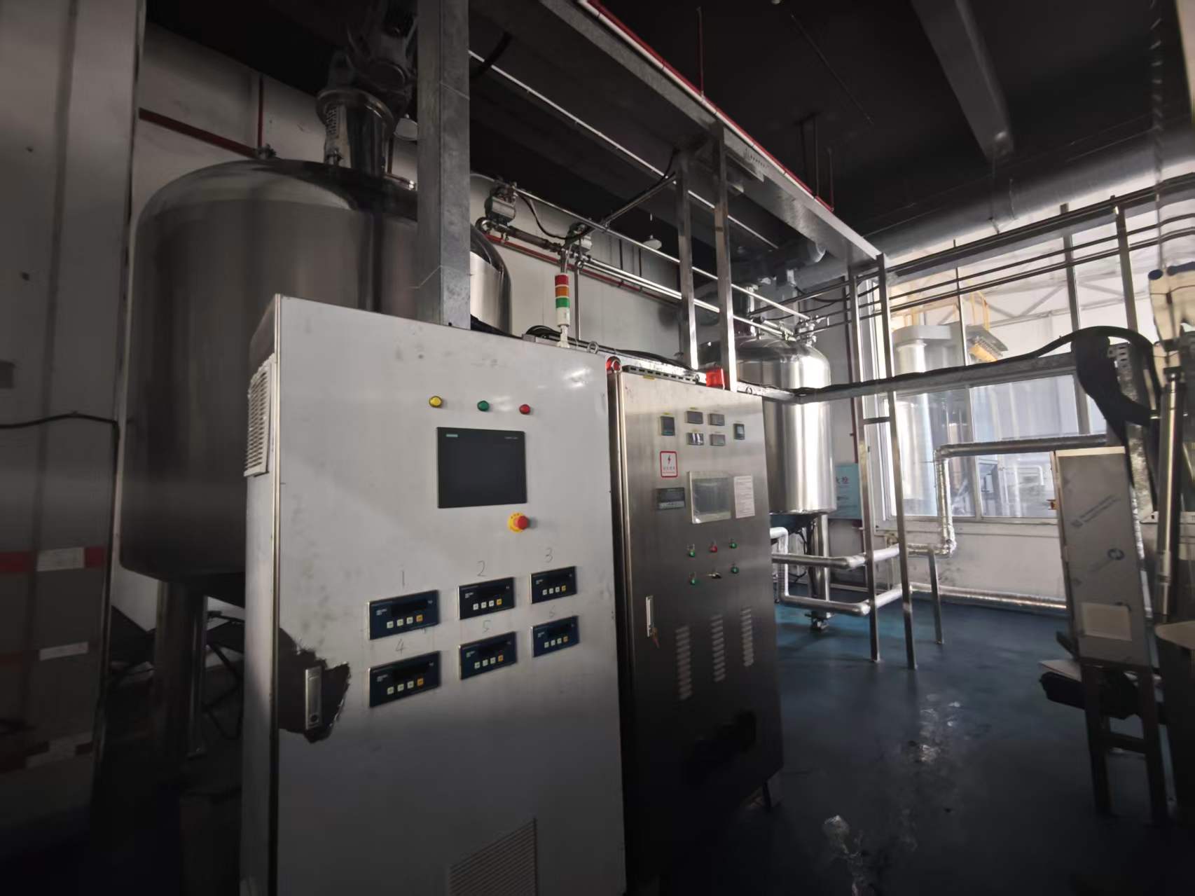 Process control panel beside stainless production equipment at Aurexene Materials.