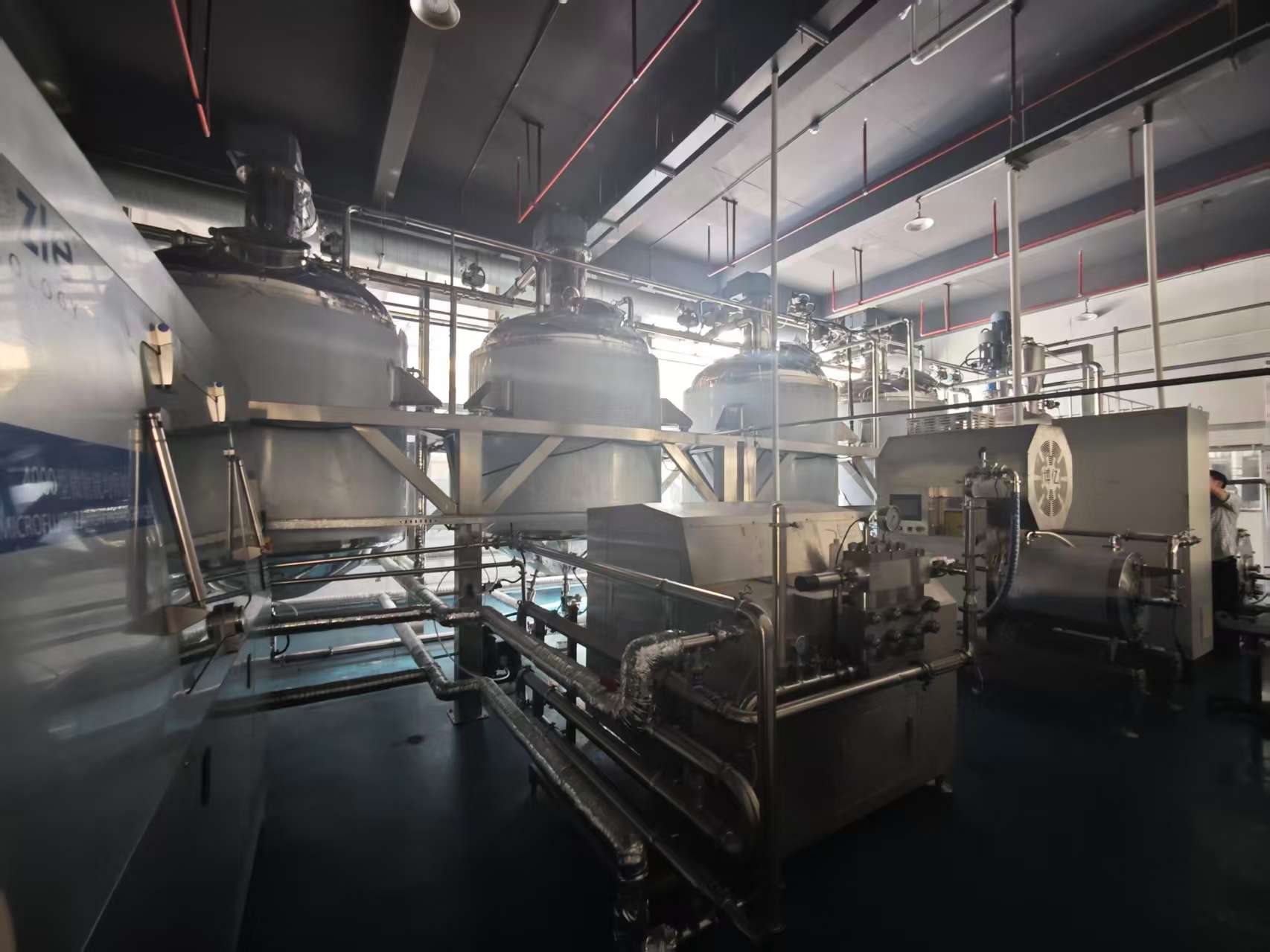 Stainless production vessels and transfer piping on the Aurexene Materials production floor.