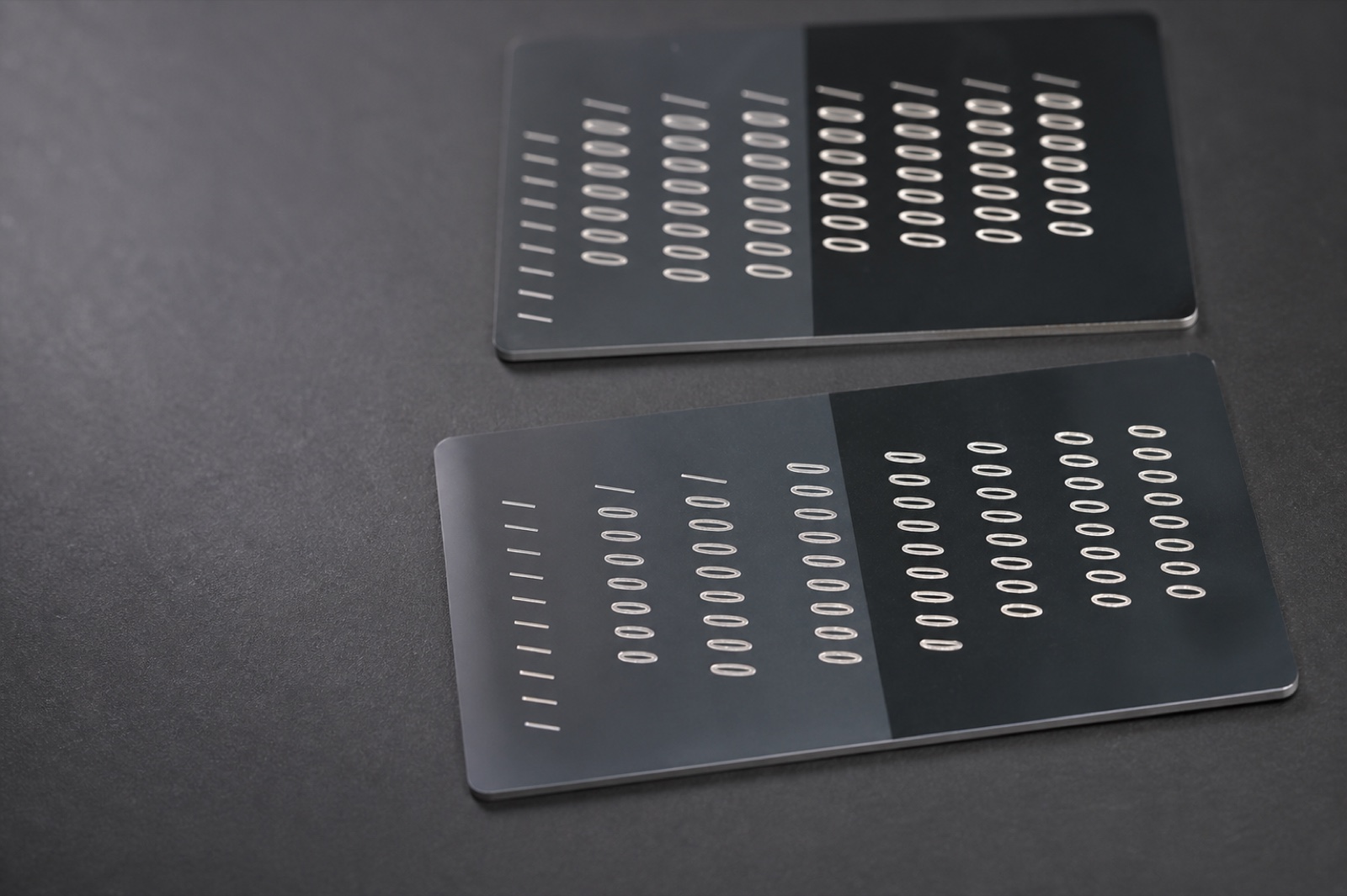 Photorealistic dark polymer test plaques with laser-marked patterns for laser-curable system application context.