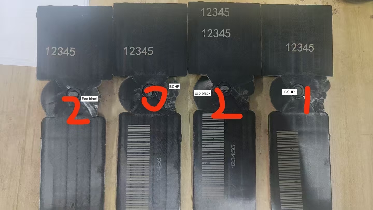Four black polymer laser-marking test samples labeled BCHP and Eco Black, showing light number marks and barcode marks.