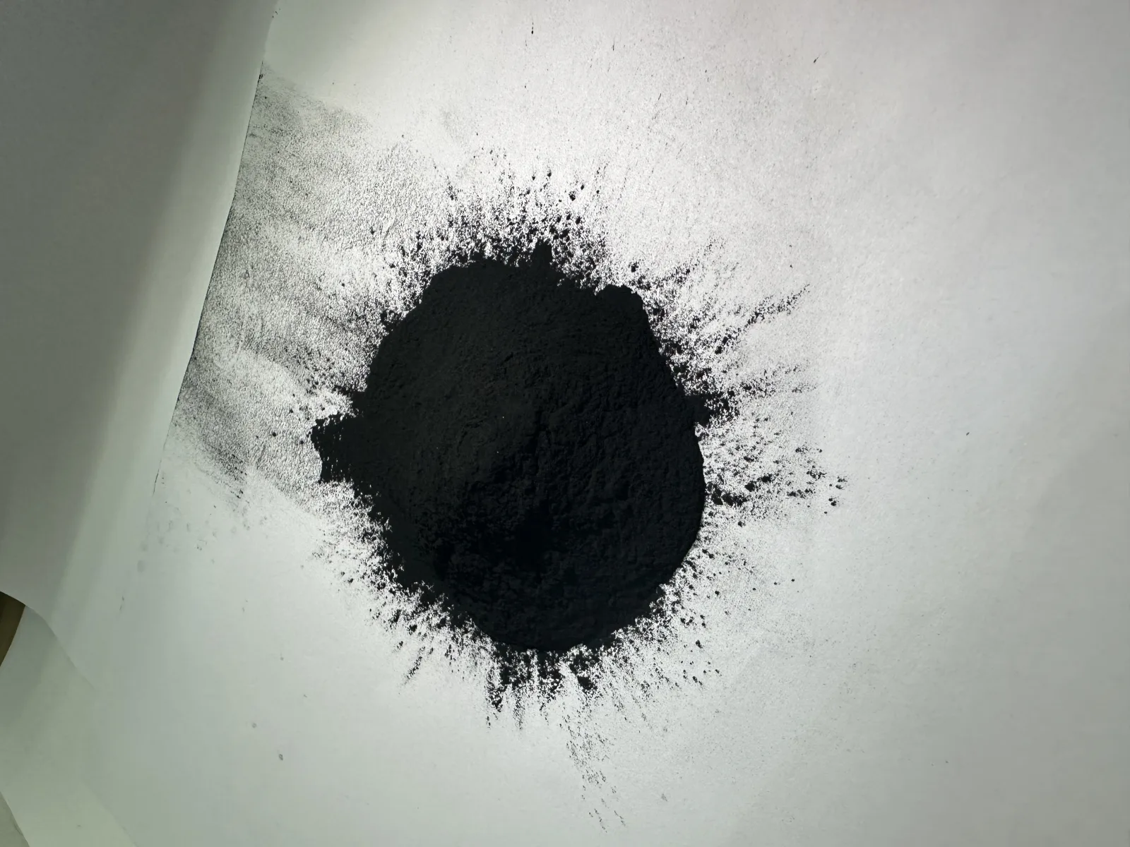 Black Eco Black composite functional black powder on a white sample surface.